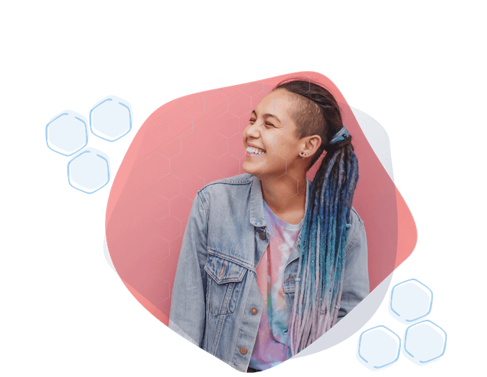 Happy smiling female student with colorful dreads outside her school classroom.